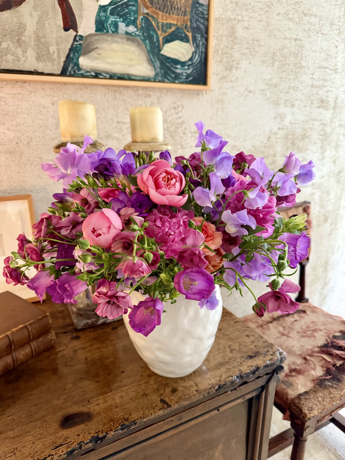 Sweet peas, campanula, and peonies on an antique chest