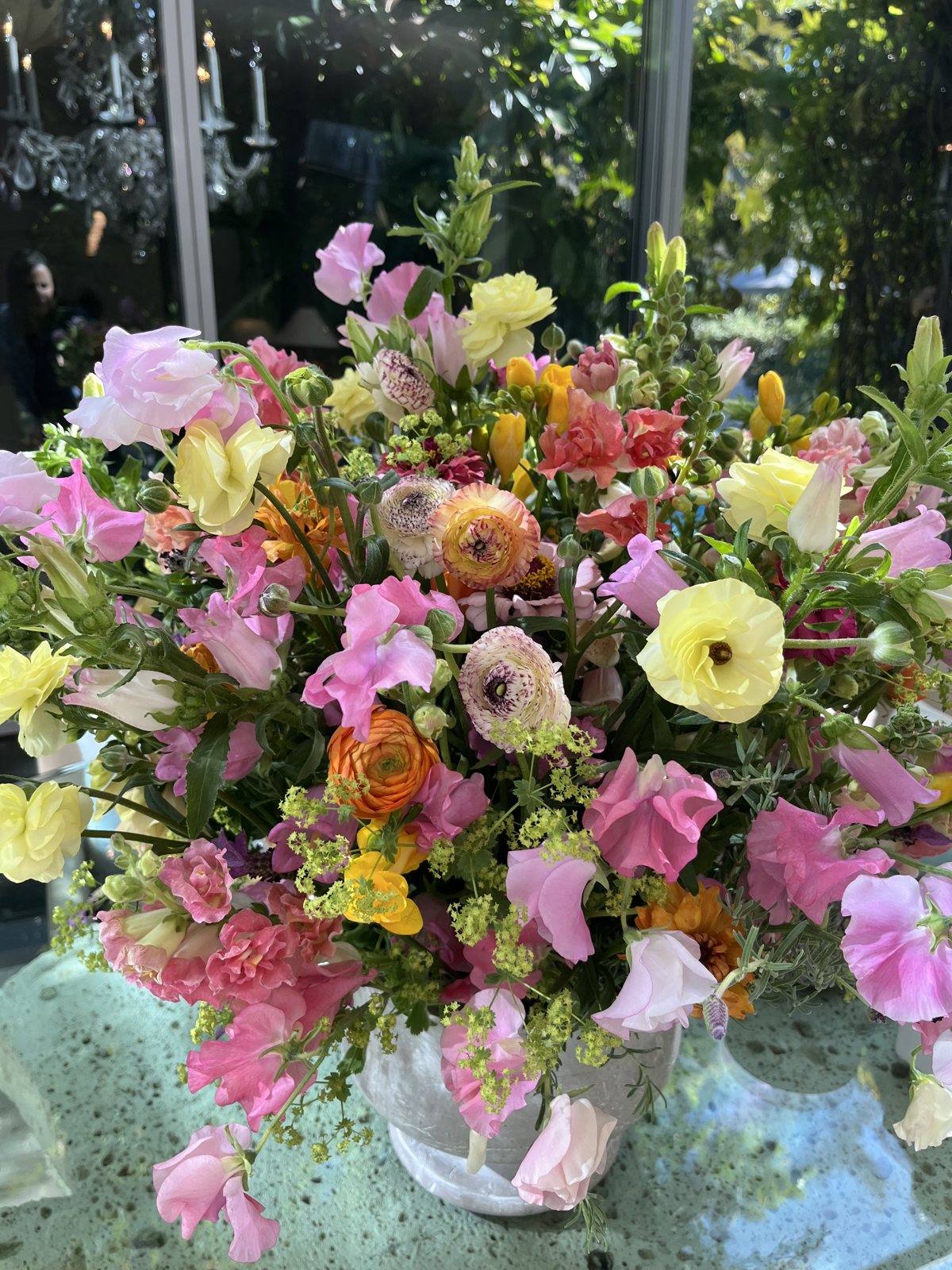 Sweet peas, snapdragons, and ranunculus in a stone urn