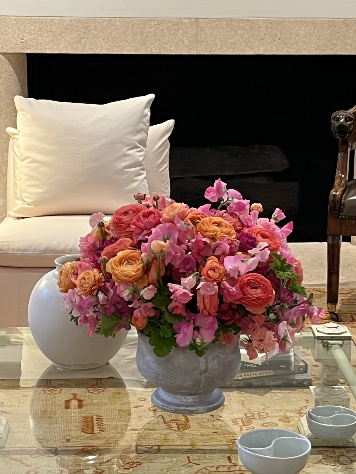 Coral ranunculus and sweet peas by the fireplace